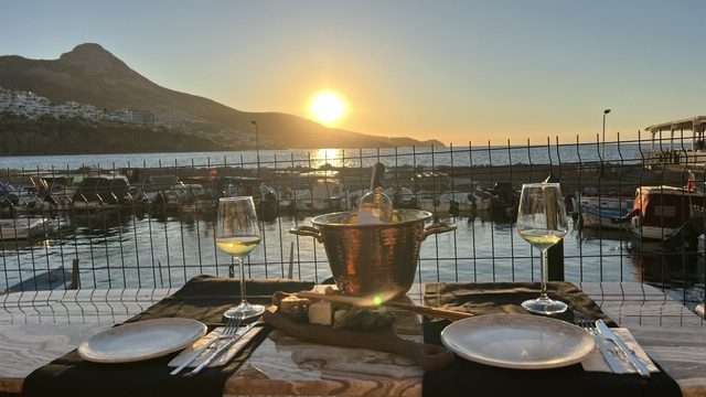 Fenha Karaburun'da gün batımında masa, deniz ve dağ manzarası